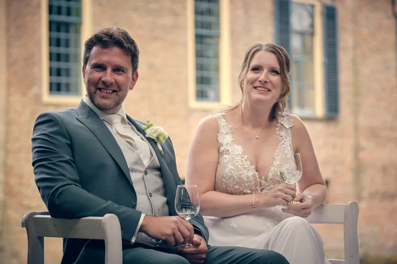 Fabian en Renée lachen om de speech, zittend voor de kasteelmuur