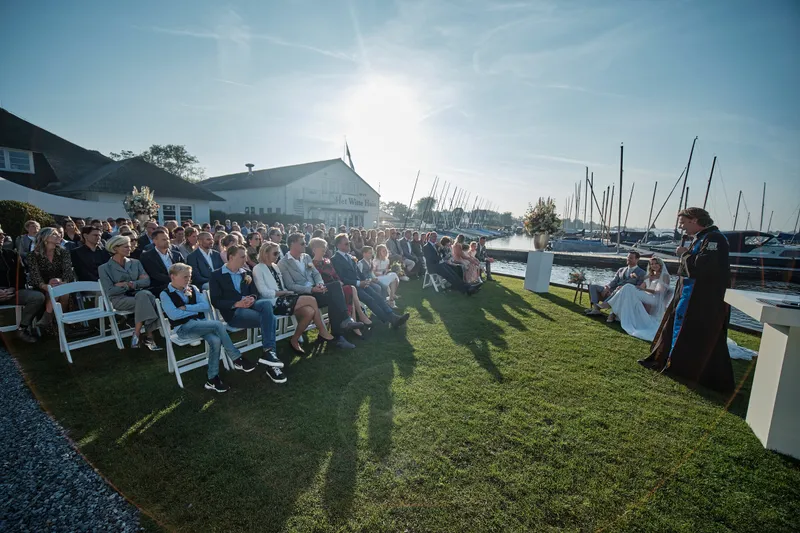 De gasten op het gazon, met de zon achter de boten op het water