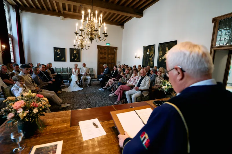 De trouwambtenaar aan de tafel, de gasten in de trouwzaal