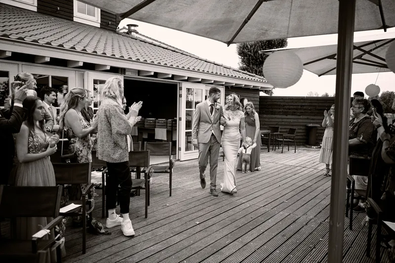 Thèron loopt over het terras naar zijn plek, de gasten staan op