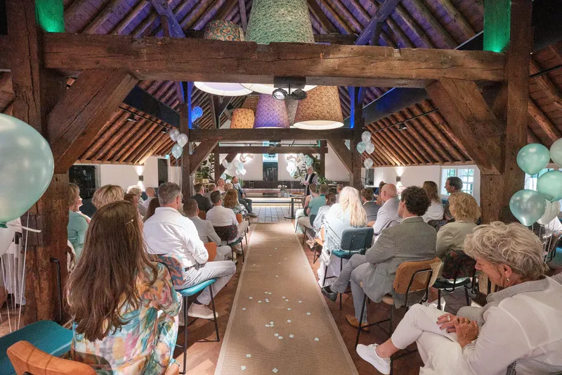De trouwzaal met houten balken en gasten langs het middenpad
