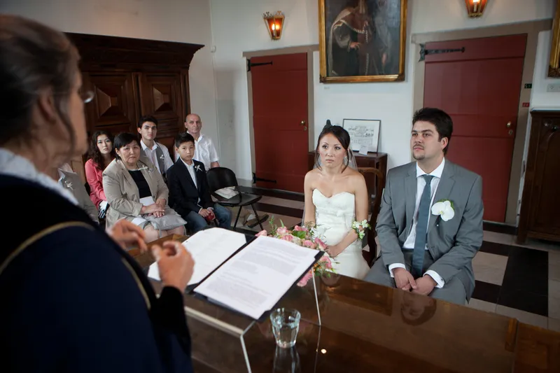 Ivan en Roza zitten voor de trouwambtenaar in de zaal
