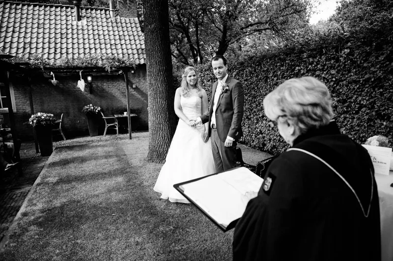 Esther en Jan-Willem tijdens de ceremonie buiten bij de boerderij, in zwart-wit