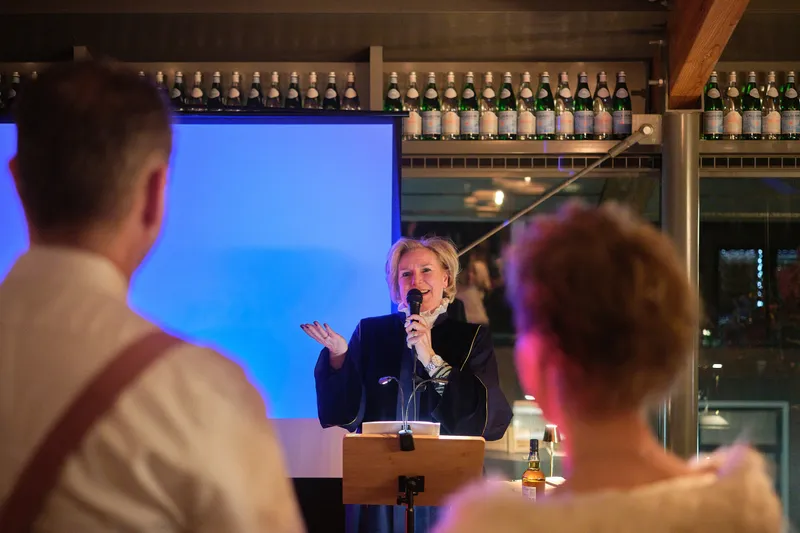 De trouwambtenaar spreekt met de microfoon bij het scherm