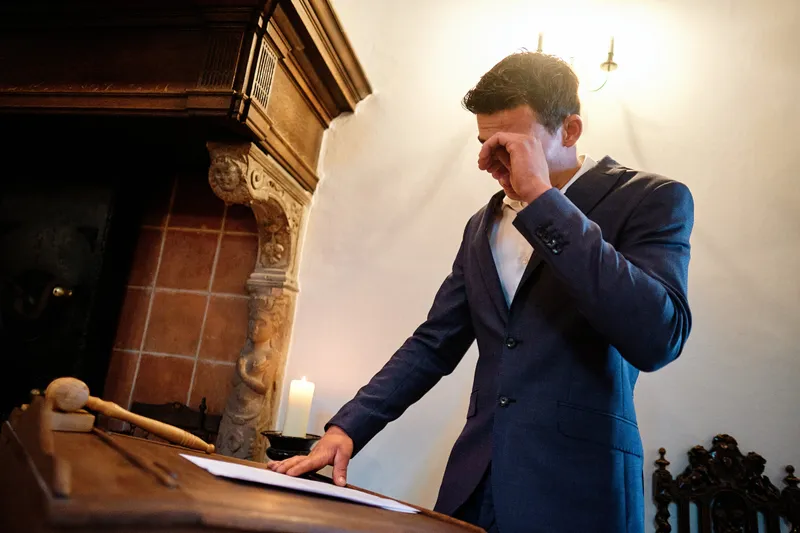 Een gast leest voor aan de houten tafel bij kaarslicht