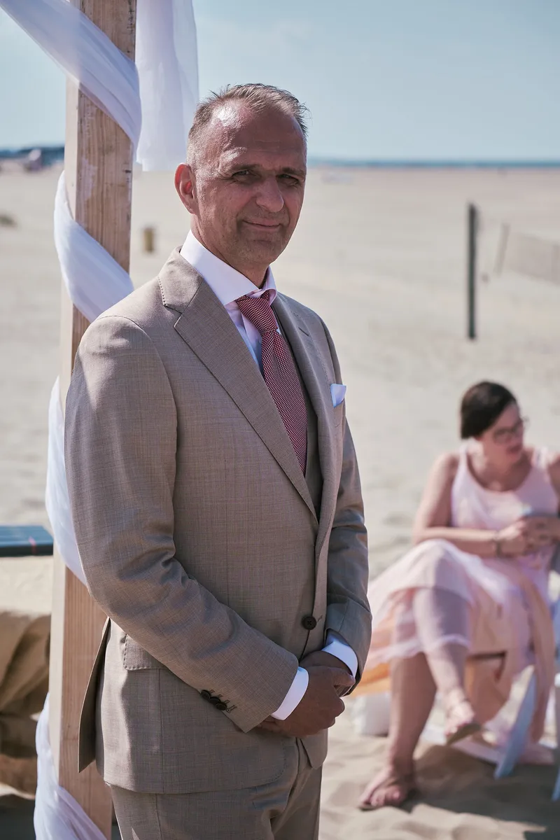 Jorg wacht onder de boog op het strand