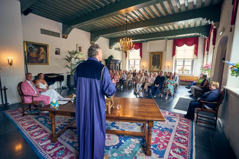De trouwambtenaar in toga voor Diliana en Olav, de gasten erachter