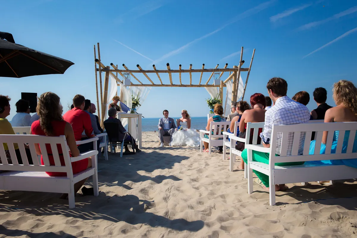De trouwboog op het strand, de gasten op witte stoelen