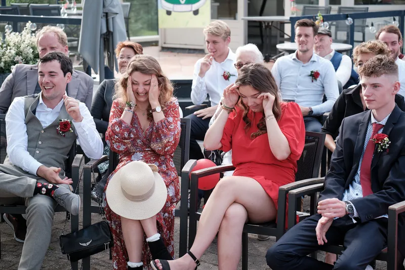 Een gast in het rood houdt lachend haar hand voor haar gezicht