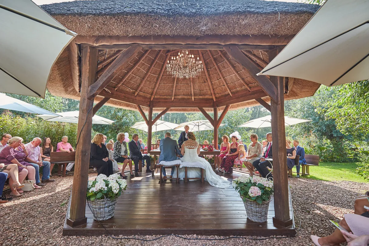 De ceremonie in het houten prieel, de gasten in rijen