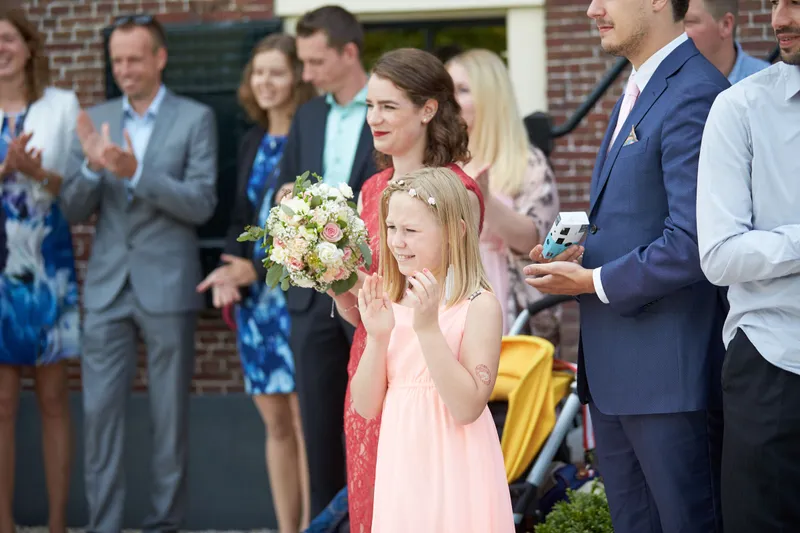 De gasten klappen, een meisje met bloemen vooraan