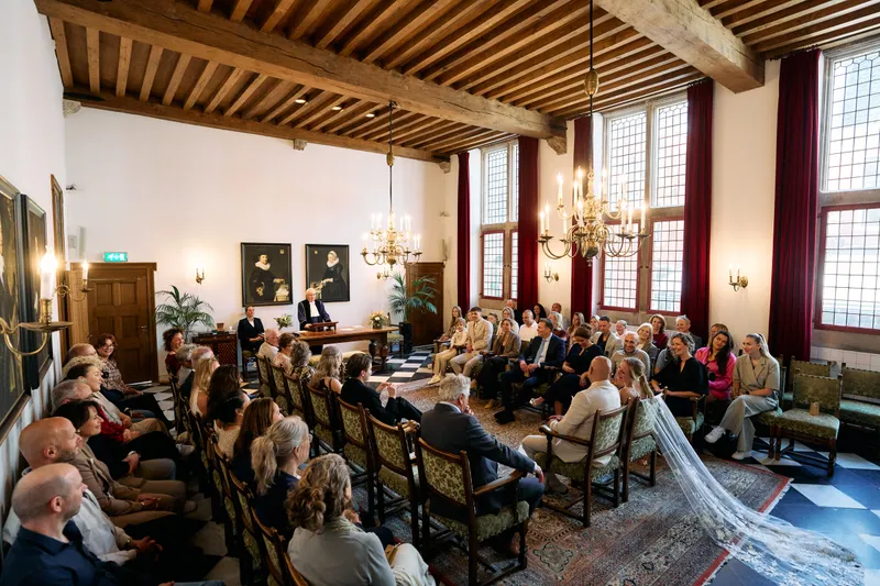De trouwzaal met de houten balken en de kroonluchter, vol gasten
