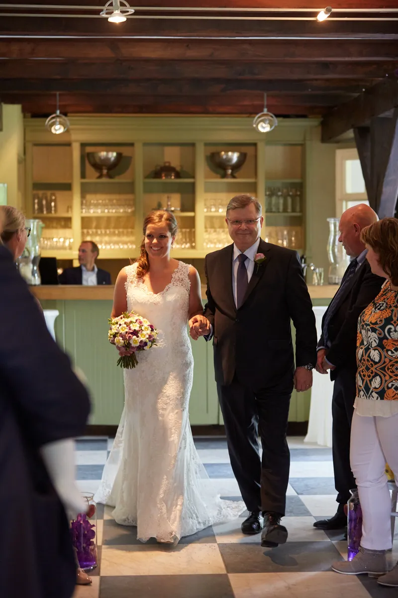 Nadine loopt aan de arm door de zaal