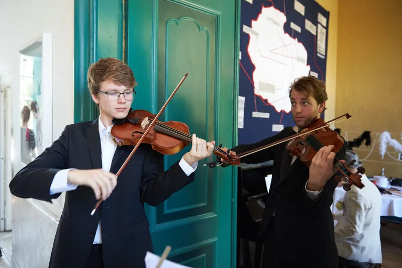 Een jonge violist speelt bij de groene deur