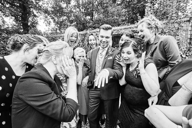 De gasten lachen dicht op elkaar, zwart-wit