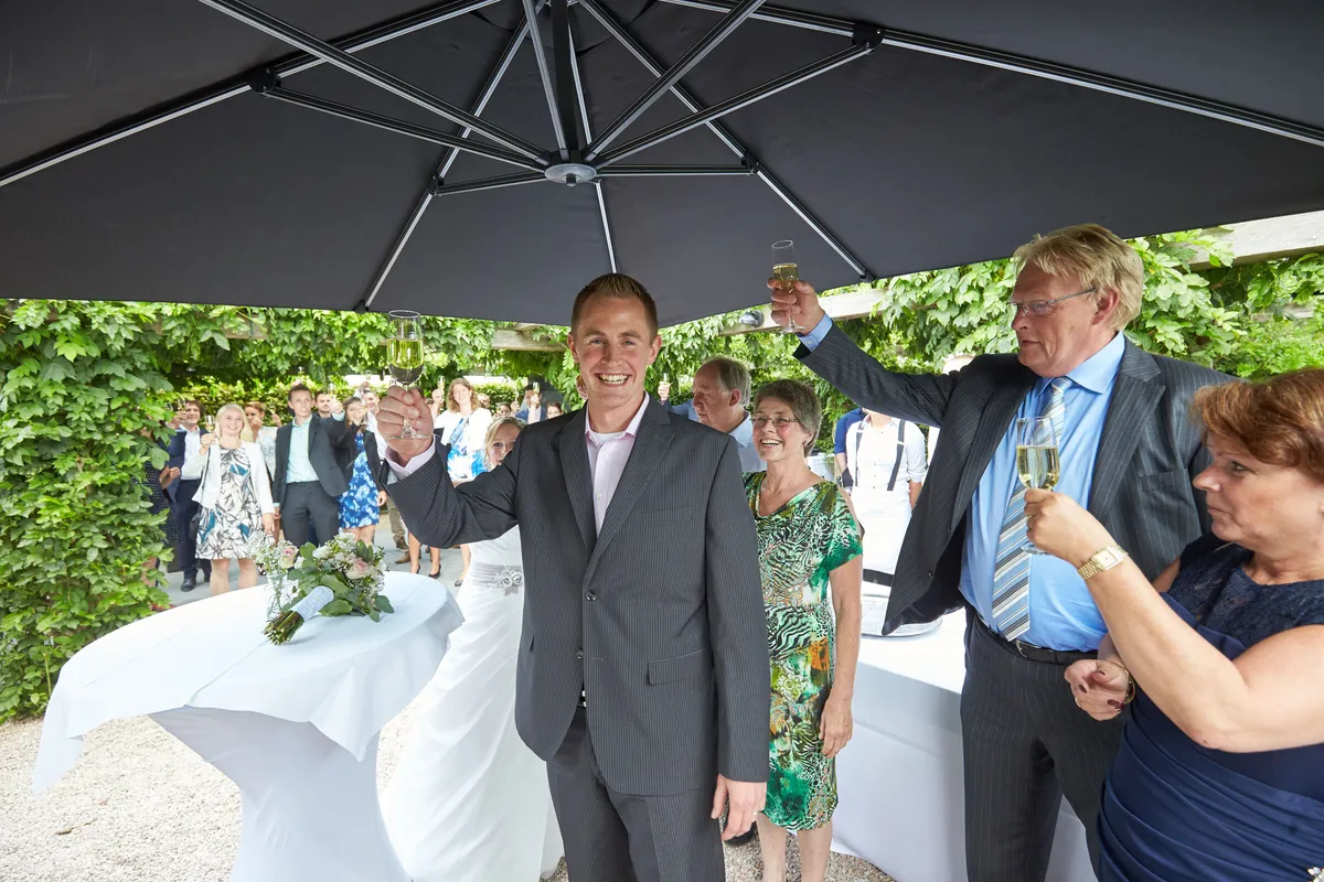 De gasten onder een parasol in de tuin, met Linsey en Tim in het midden