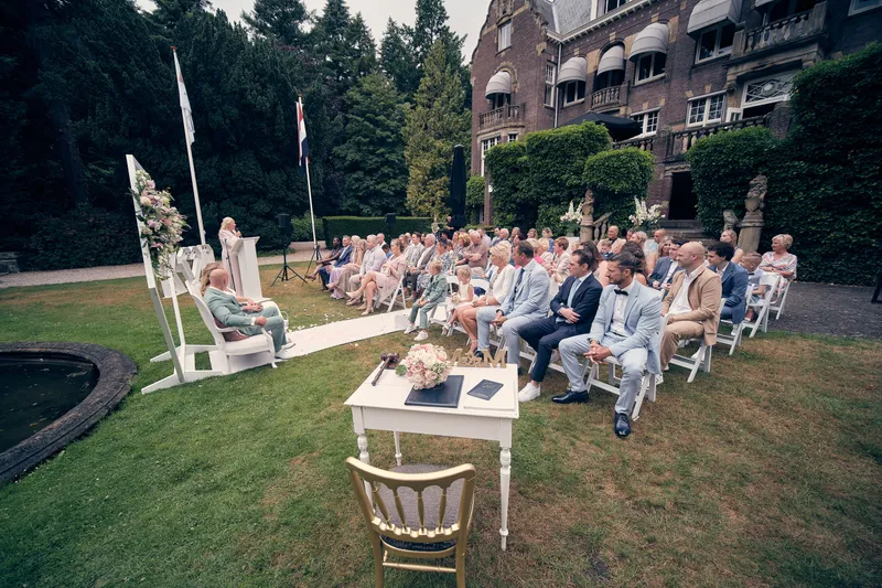 De ceremonie in de kasteeltuin, de gasten op witte stoelen voor het kasteel