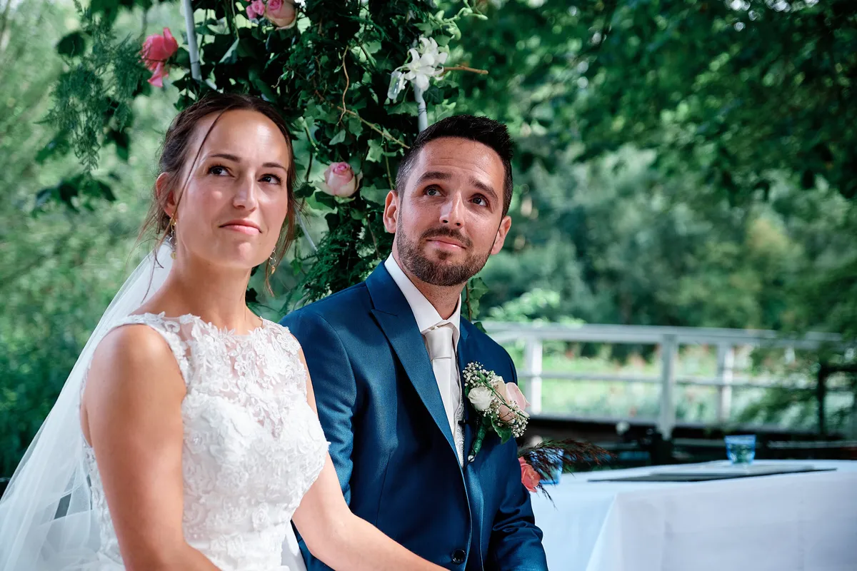 Tessa en Jeroen zitten naast elkaar tijdens de ceremonie in de tuin
