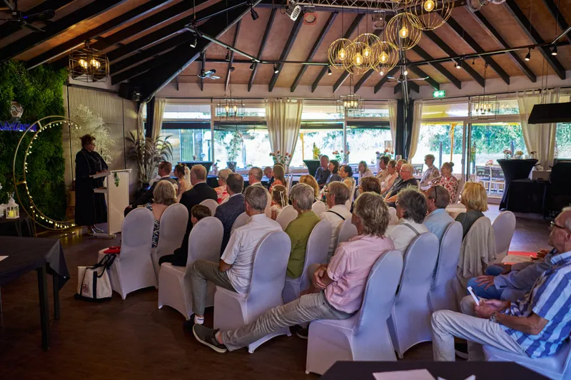 De zaal van AA-Zicht met de gasten op witte stoelen