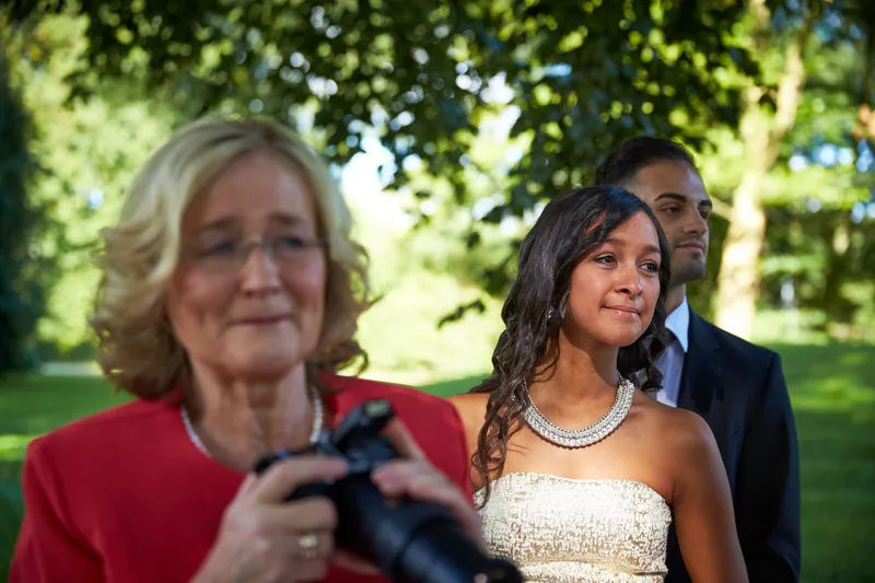 Een gast met een camera en een gast in een strapless jurk wachten op de bruid
