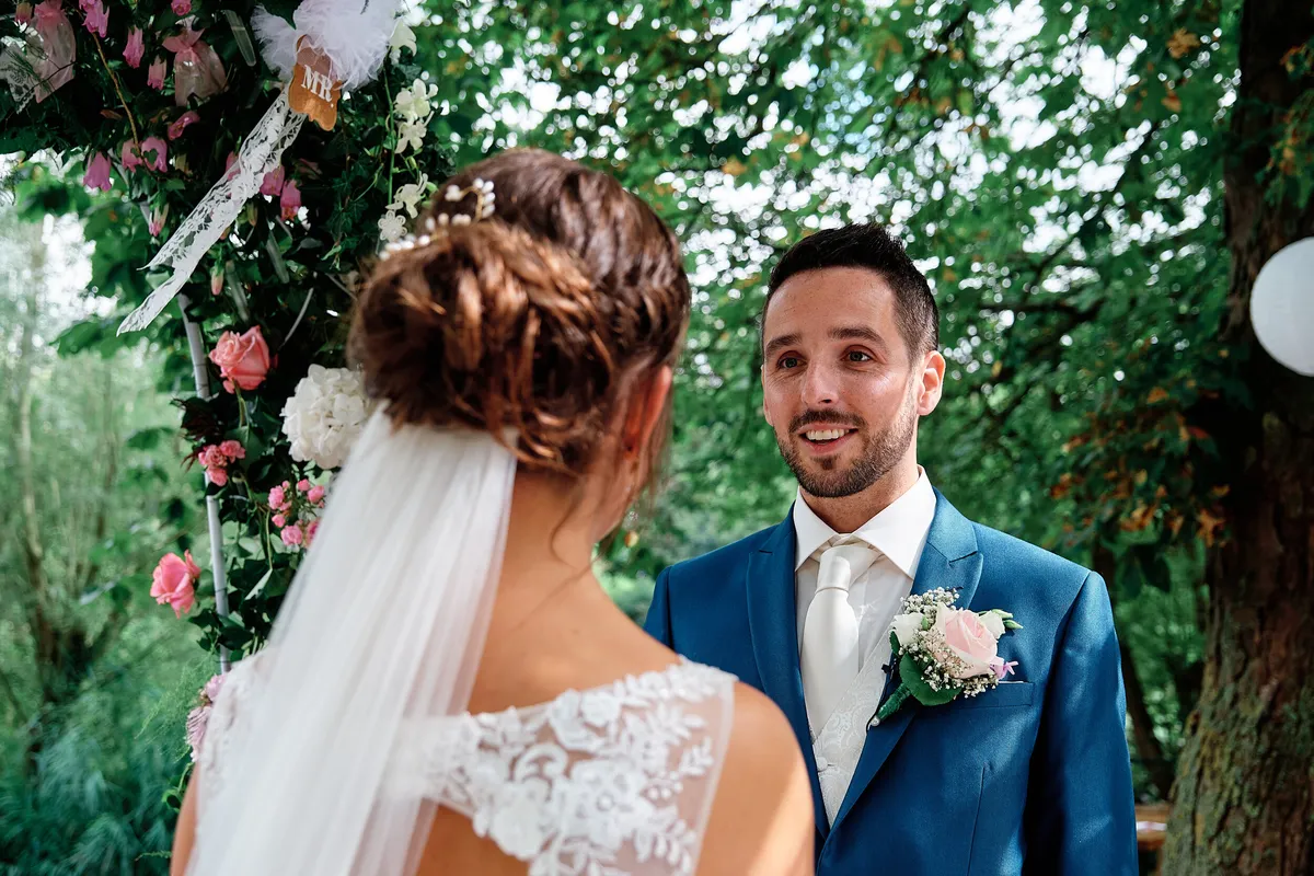 Tessa en Jeroen lachen naar elkaar onder de bloemenboog