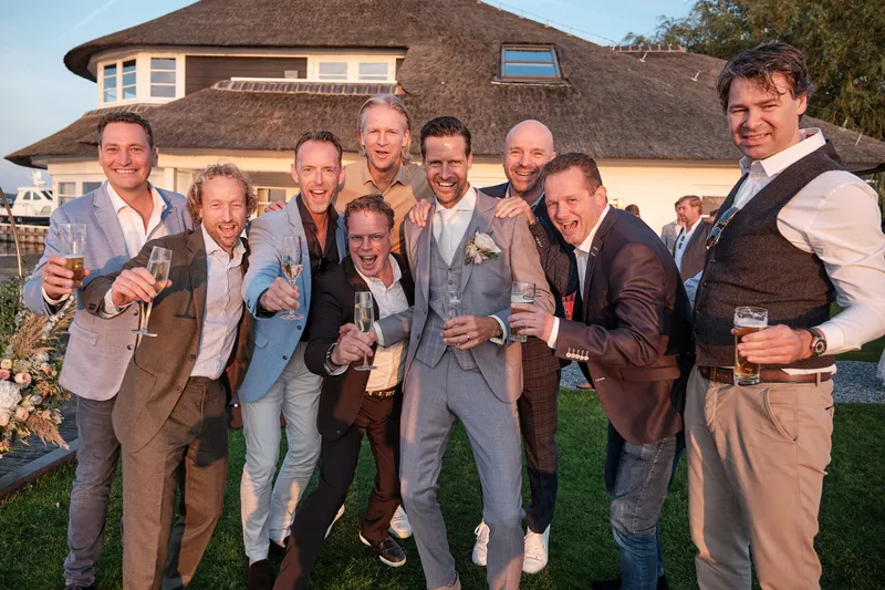 De mannen proosten lachend voor het huis
