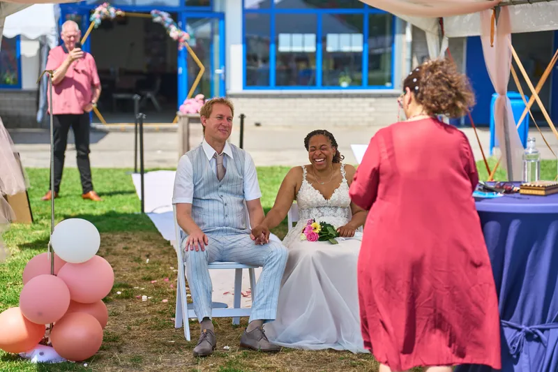 De ceremonie onder de tent met de gasten op witte stoelen