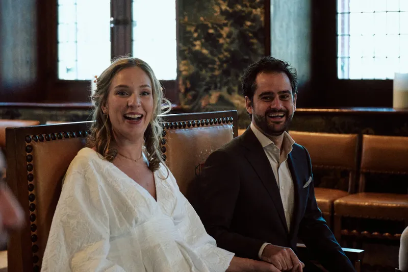 Anouk lacht naast Raphaël op de houten stoelen