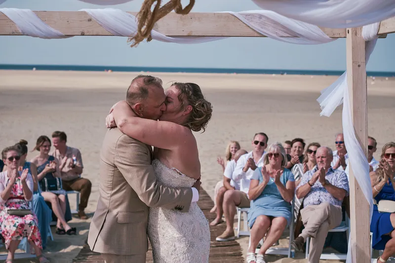 Jorg en Mirjam omhelzen elkaar onder de boog, de gasten erachter