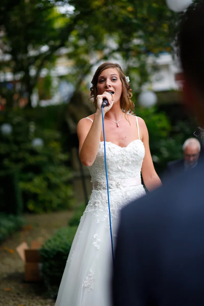 Aniek zingt met een microfoon in de tuin