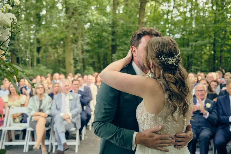 Fabian en Renée kussen elkaar onder de bomen, tussen de gasten