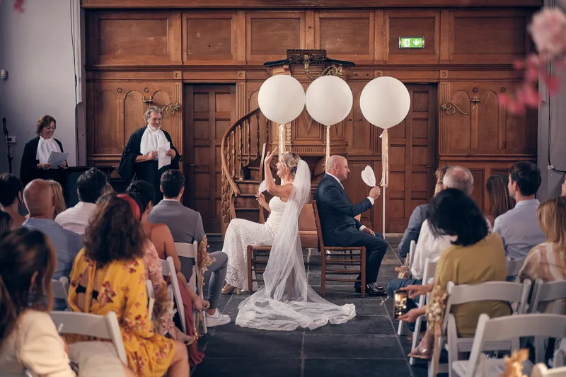 Elles en Bram voor de trouwambtenaar, tussen de witte ballonnen