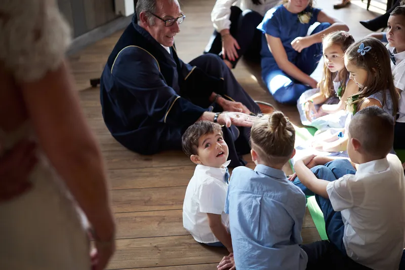 De kleinkinderen zitten op de grond rond de trouwambtenaar