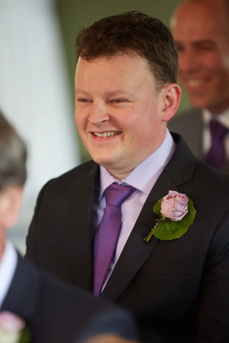 Een gast met een roze roos lacht