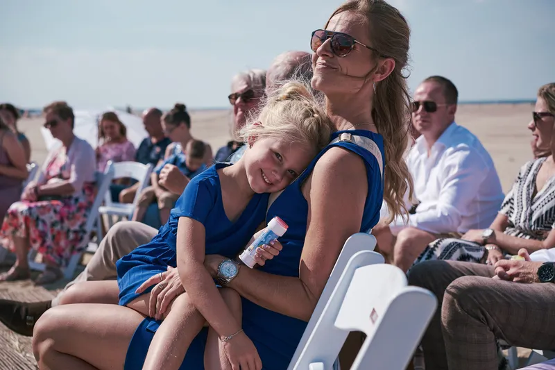 Gasten lachen op hun stoelen op het strand