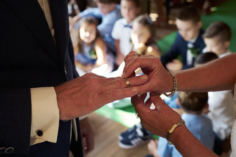 Cees schuift de ring om de vinger van Jopie, de kleinkinderen kijken toe