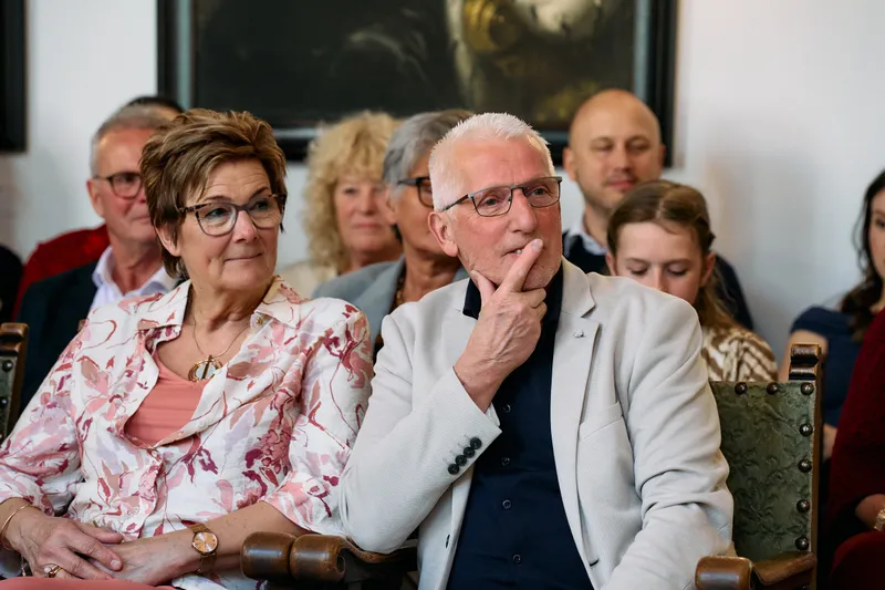 Een oudere gast luistert met zijn hand aan zijn kin