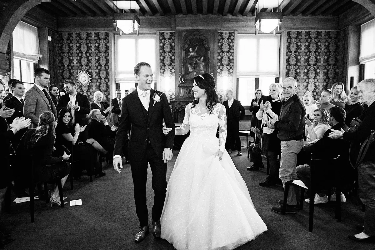 Kimberley en Mike lopen de trouwzaal uit tussen de gasten