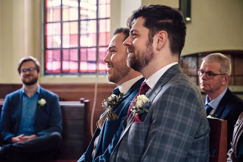 Joey en Twan lachen samen, met de gasten in de bank achter hen