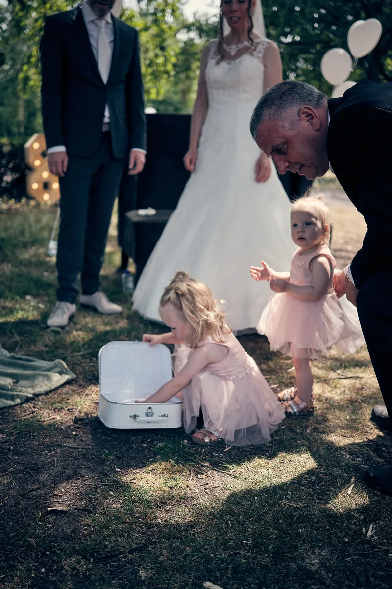 De dochtertjes bij het witte koffertje met de ringen, opa buigt zich naar hen toe