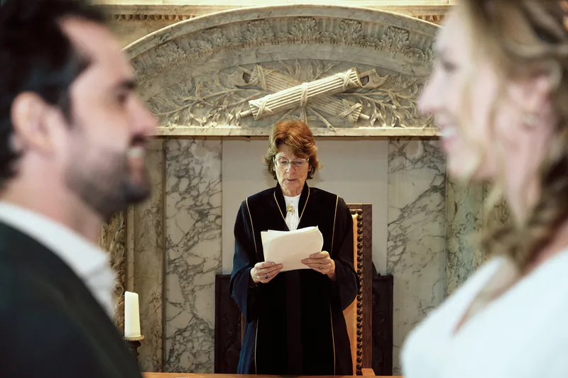 Raphaël lacht, met de trouwambtenaar tussen hen in