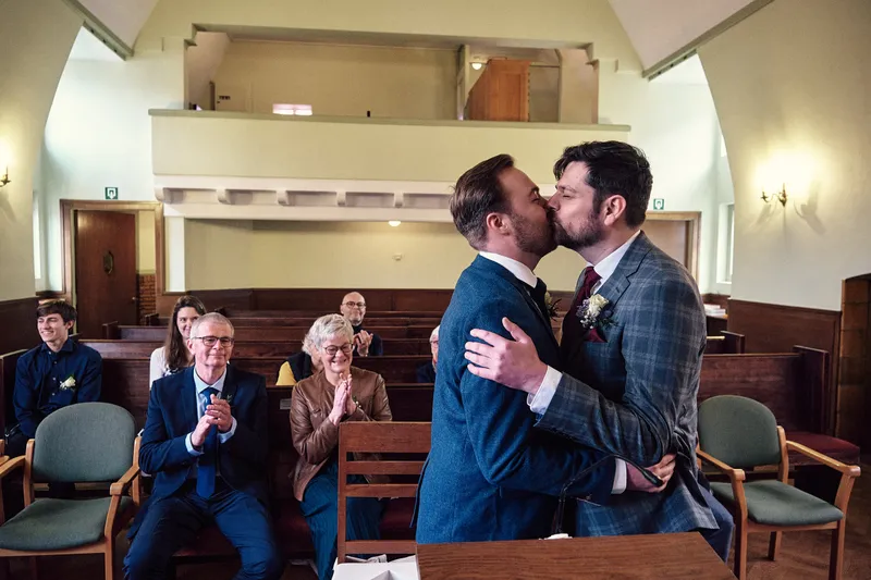 Joey en Twan kussen elkaar, de gasten klappen