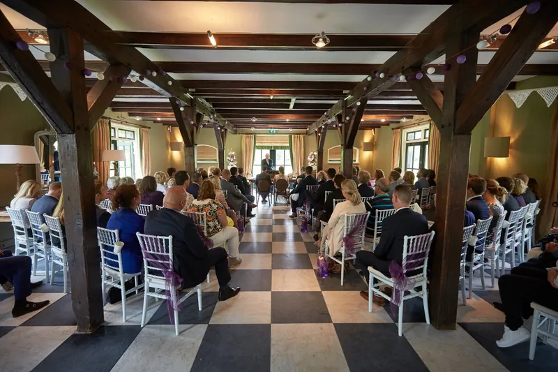 De zaal onder de houten balken, met alle gasten op hun stoelen
