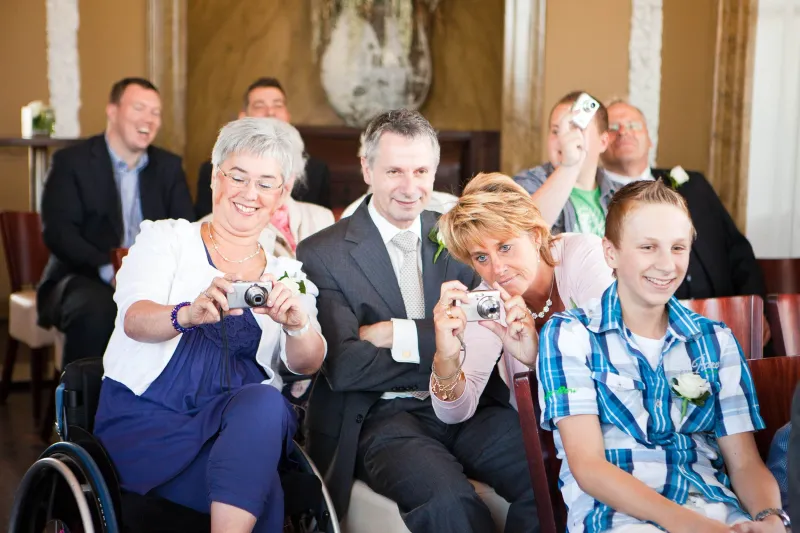 Gasten zitten vooraan bij de ceremonie en fotograferen met compactcamera’s