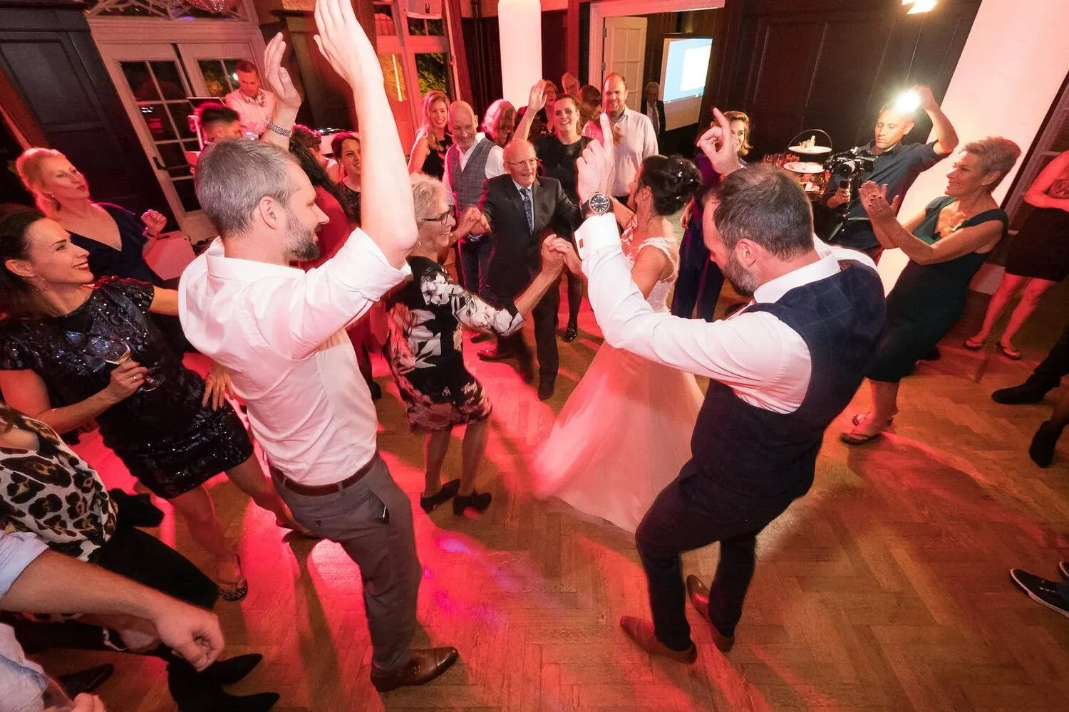 Gasten dansen uitgelaten in rood licht op het feest