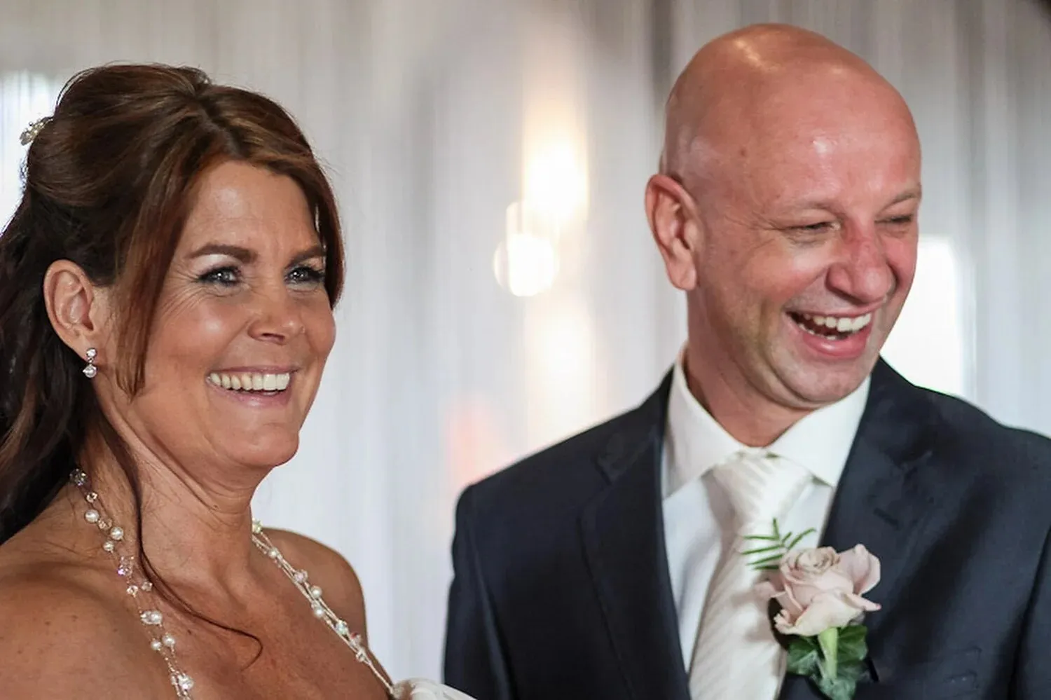 Bruid en bruidegom lachen uitbundig tijdens de ceremonie