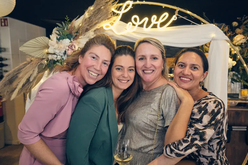 Vier vriendinnen onder de bloemenboog met ‘Love’