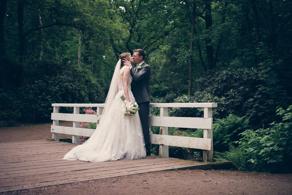 Yvo en Marjolijn kussen op een wit bruggetje in het bos van Clingendael