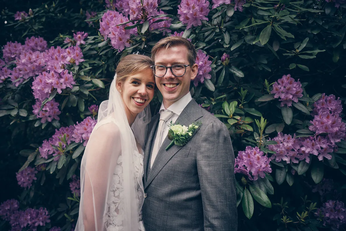 Yvo en Marjolijn lachen voor paarse rododendrons in de Japanse tuin