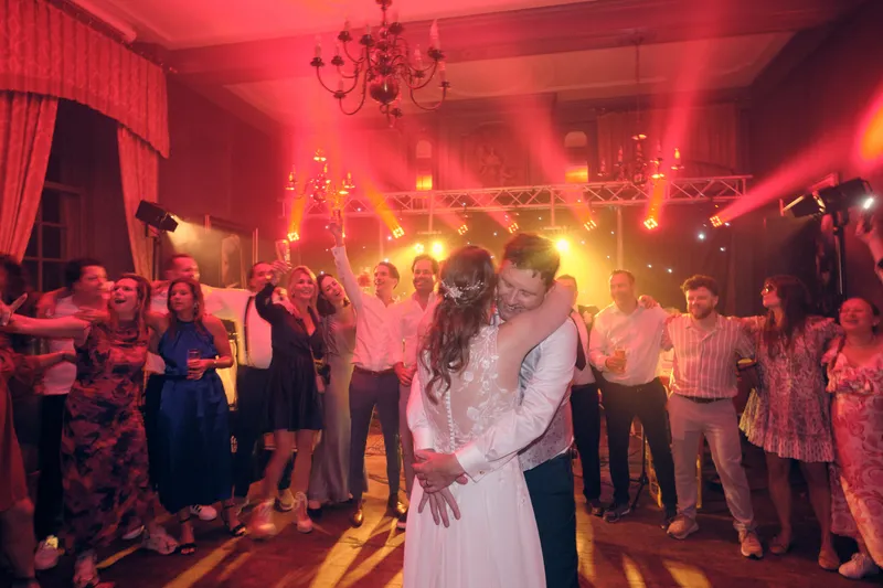 Fabian en Renée dansen in rood licht, de gasten staan eromheen